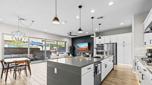A modern kitchen with a central island, white cabinetry, and stainless steel appliances. - Luna Luxe Rooftop Retreat | 3BR • 2.5BA • Pool (Scottsdale)