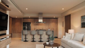 A modern living room with a sofa, a coffee table, and a TV. There is a kitchen area with a bar and stools. - Marina Vallarta Beautiful apartment with jacuzzi (Puerto Vallarta)