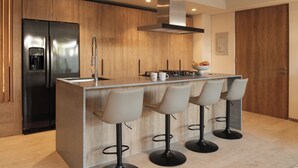 A modern kitchen with a stainless steel refrigerator, a built-in coffee maker, and a bar area with four stools. - Marina Vallarta Beautiful apartment with jacuzzi (Puerto Vallarta)