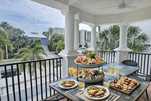 Un balcon avec une table dressée pour un repas, où l’on peut trouver une variété de plats et de boissons.