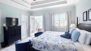 A bedroom with a bed, a TV, a dresser, and a ceiling fan.