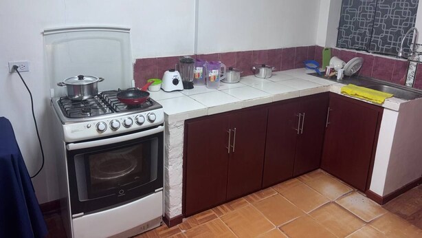 A compact kitchen with a gas stove, oven, and a small countertop with various kitchen items.