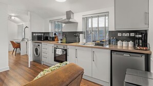 A modern kitchen with a dishwasher, oven, microwave, and a coffee maker.