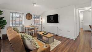 A modern living room with a brown sofa, a wooden coffee table, and a TV mounted on the wall.