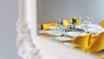 A dining table set with plates, glasses, and cutlery, with yellow chairs and a vase of flowers.