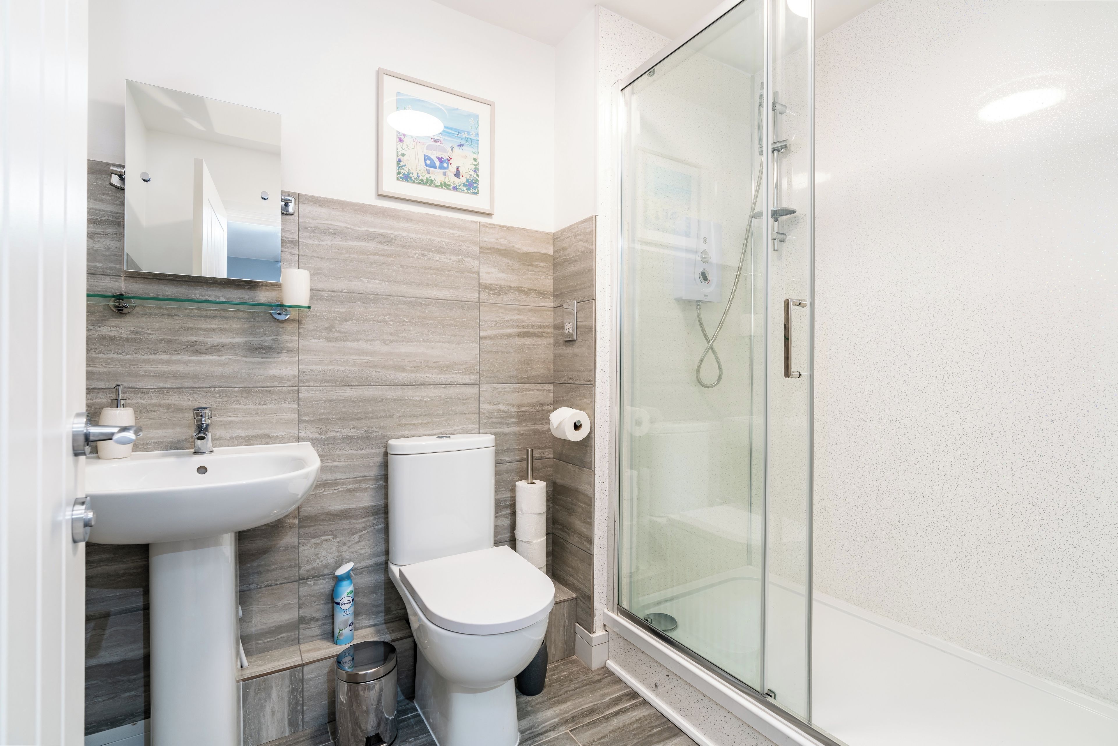 A modern bathroom with a glass shower enclosure, a pedestal sink, and a toilet.