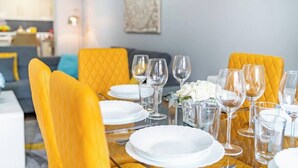 A dining area with a table set for four, yellow upholstered chairs, white plates, and clear wine glasses. - Fairfax Close, Amesbury, Wiltshire, SP47ST, United Kingdom (Amesbury)