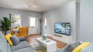 A modern living room with a grey sofa, yellow cushions, a white coffee table, and a flat-screen TV on a white stand. - Fairfax Close, Amesbury, Wiltshire, SP47ST, United Kingdom (Amesbury)