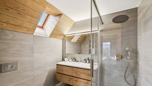 A modern bathroom with a wooden vanity, a glass shower enclosure, and a skylight. - Starlight by Mrs Miggins (Crans-Montana)