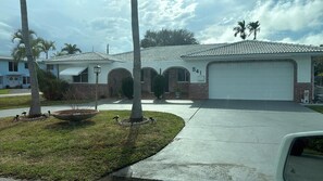 A residential house with a garage, a driveway, and a lawn with palm trees. - The Cove  Beach Pool House Walk to Beach, Dining & Shopping (Deerfield Beach)