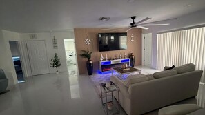 A modern living room with a flat-screen TV, a sofa, a coffee table, and a fireplace. - The Cove  Beach Pool House Walk to Beach, Dining & Shopping (Deerfield Beach)