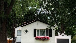 Ein zweistöckiges Haus mit weißer Fassade, schwarzen Fensterläden und einer Garage.
