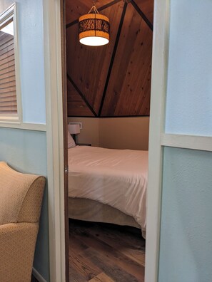 Ein Schlafzimmer mit Holzboden, einem Bett und einer Pendelleuchte.