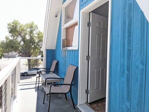 A balcony with two chairs and a table, a door, and a security camera.