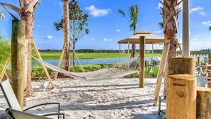 Une zone de plage avec des hamacs, un kiosque en bois et une vue sur un lac.