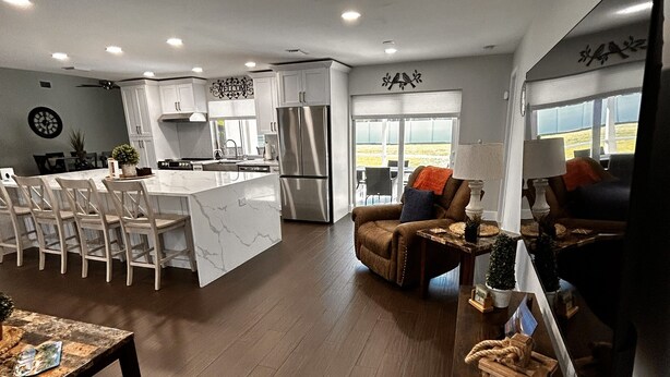 Una cocina moderna con armarios blancos, una isla grande y un refrigerador empotrado.