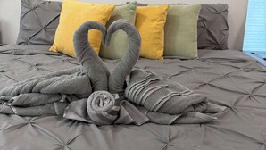 Una cama con edredón gris y almohadas en amarillo y verde.
