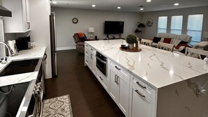 Una cocina moderna con armarios blancos, una isla grande y un horno empotrado.