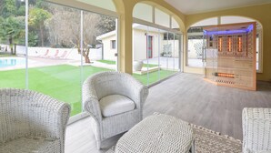 Un interior moderno con mobiliario de mimbre, ventanas amplias y vista a la piscina.