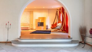Una sala de estar moderna con una pared de piedra, una silla colgante, un sofá y una chimenea.