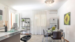 Una cocina moderna con comedor, que incluye un refrigerador, una araña y una mesa de comedor con sillas.