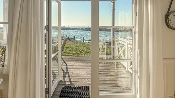 Una terraza de madera con vista al mar y un muro de piedra.