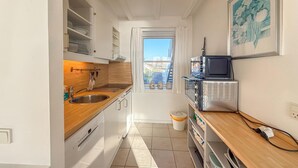 Una cocina compacta con fregadero, estufa y microondas.