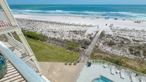 A beach view from a balcony with a pool and lounge chairs. - Dolphin Key 3C | Beachfront | Pool | Boat Slips | My Beach Getaways (Orange Beach)