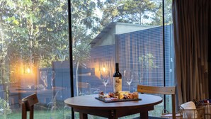 A dining area with a table set for two, a bottle of wine, and a glass of wine on the table. - Cozy Cabin, Jacuzzi, AC, Fireplace and Hot water. (Jarabacoa)