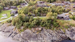An aerial view of a residential area with houses surrounded by dense forest and rocky terrain.