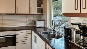 A kitchen with white cabinets, a Bosch oven, a microwave, a sink, and a coffee maker.