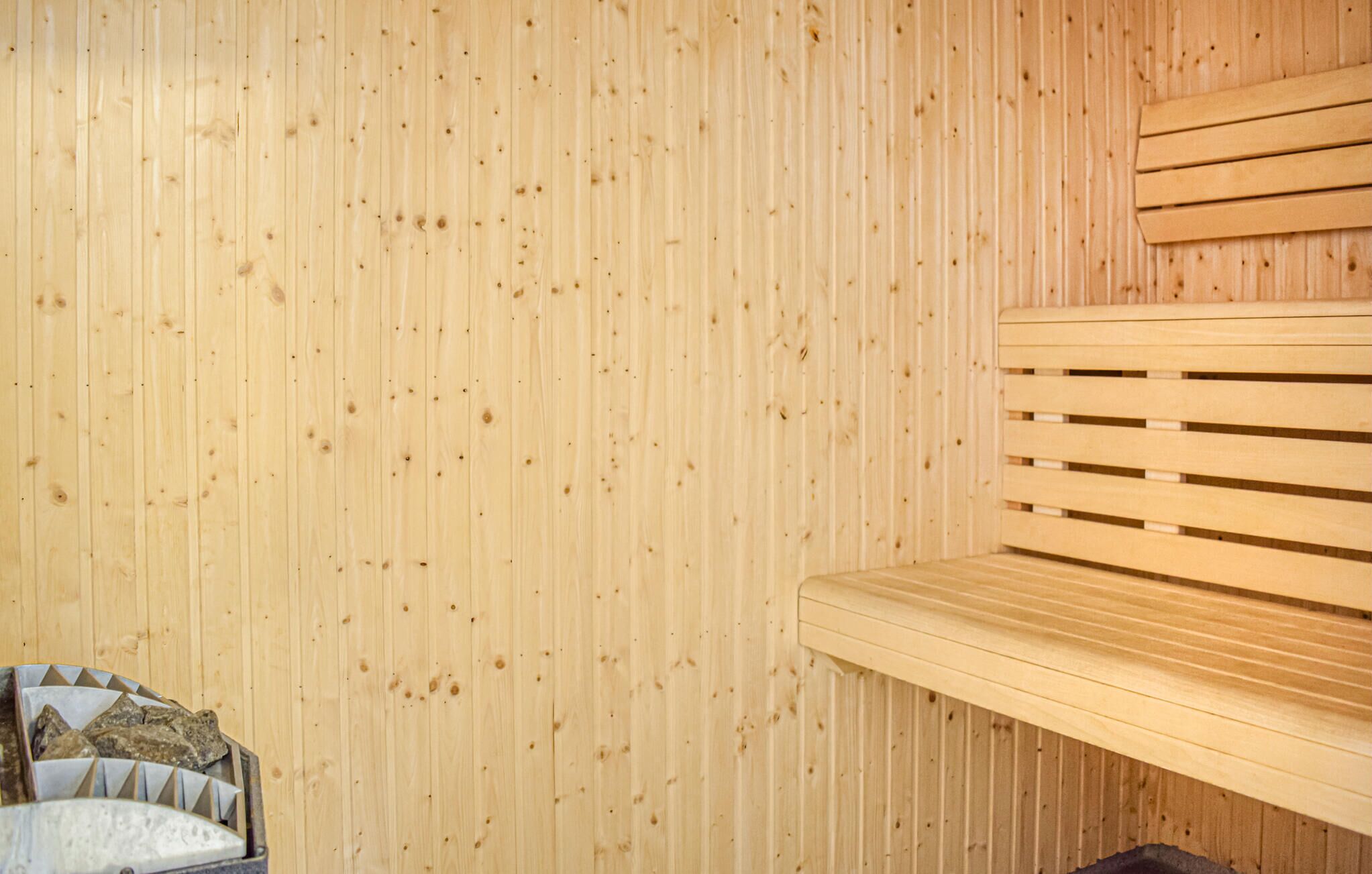 Una sauna de madera con bancos y un banco de piedra.
