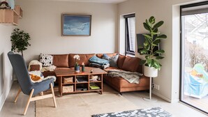 A living room with a brown leather sofa, a blue armchair, a coffee table, and a potted plant. - 3 bedroom beautiful apartment in Voss (Voss)