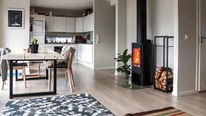A modern kitchen with white cabinets, a dining area with a table and chairs, and a black wood-burning stove. - 3 bedroom beautiful apartment in Voss (Voss)