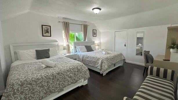 Een hotelkamer met twee bedden, een zithoekje en een spiegel.