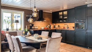 A modern kitchen with dark cabinets, a wooden countertop, and a dining area with a table and chairs. - Stunning home in Bjorli with sauna (Bjorli)