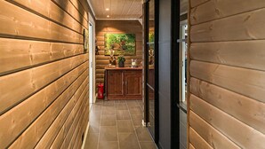 A narrow hallway with wooden walls and a tiled floor, leading to a room with a wooden cabinet and a painting on the wall. - Stunning home in Bjorli with sauna (Bjorli)