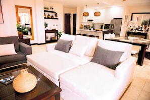 A living room with a sofa, a coffee table, and a dining area with a table set for two.