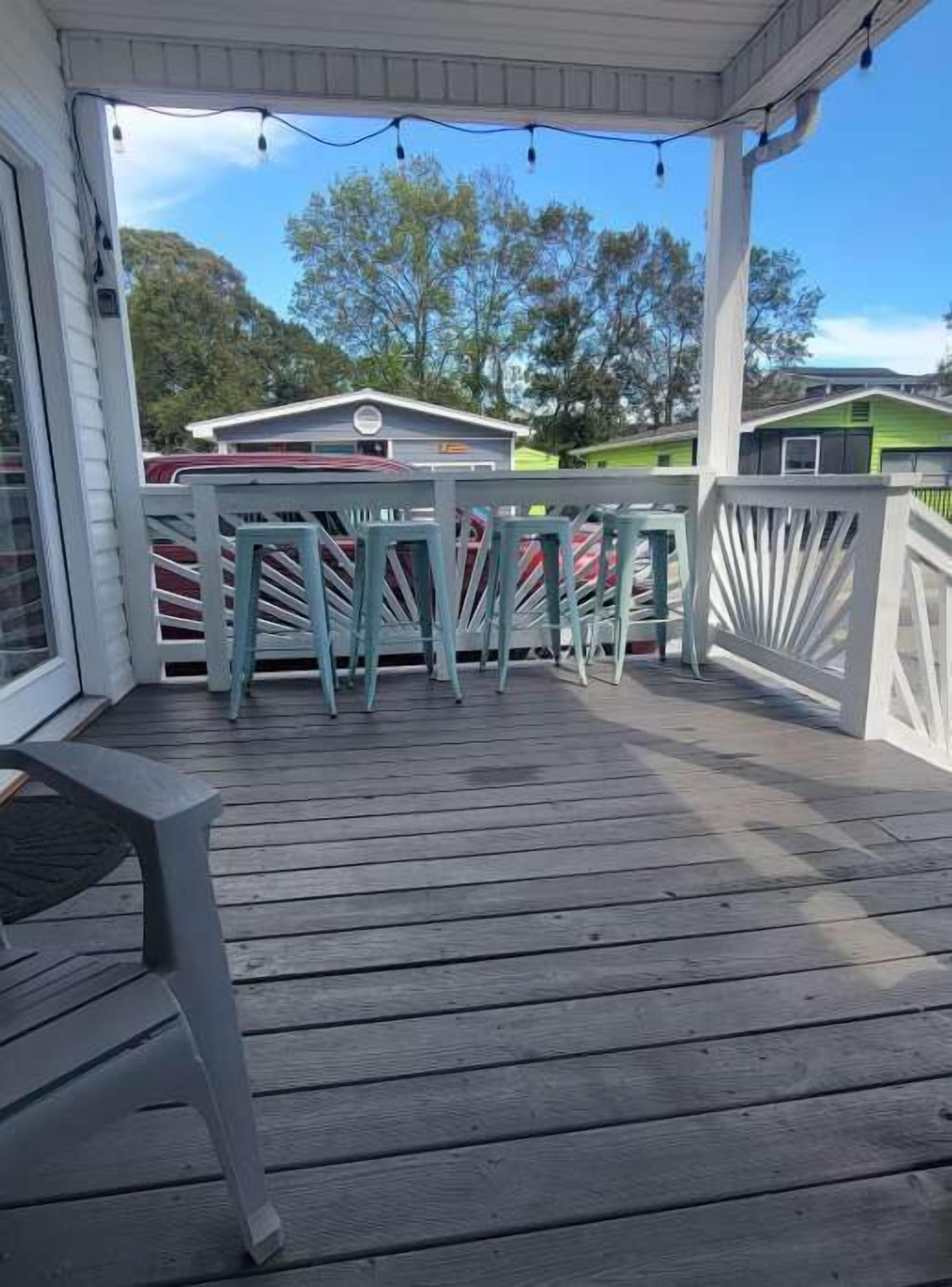 Un espace extérieur abrité, doté d’une terrasse en bois, de rampes en métal et d’un banc.