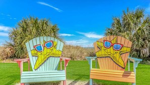 Deux chaises de plage ornées de motifs d’étoiles de mer, sous un ciel d’un bleu limpide.