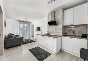 Una cocina moderna con armarios blancos, una encimera gris y un microondas integrado.