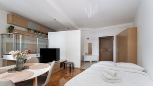 Una camera d'albergo moderna con un letto, una scrivania, una TV, un'area pranzo e un armadio.