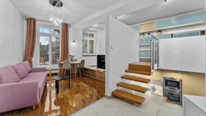 Un soggiorno moderno con un divano rosa, una scala in legno e una cucina a scomparsa completa di forno a microonde e forno.