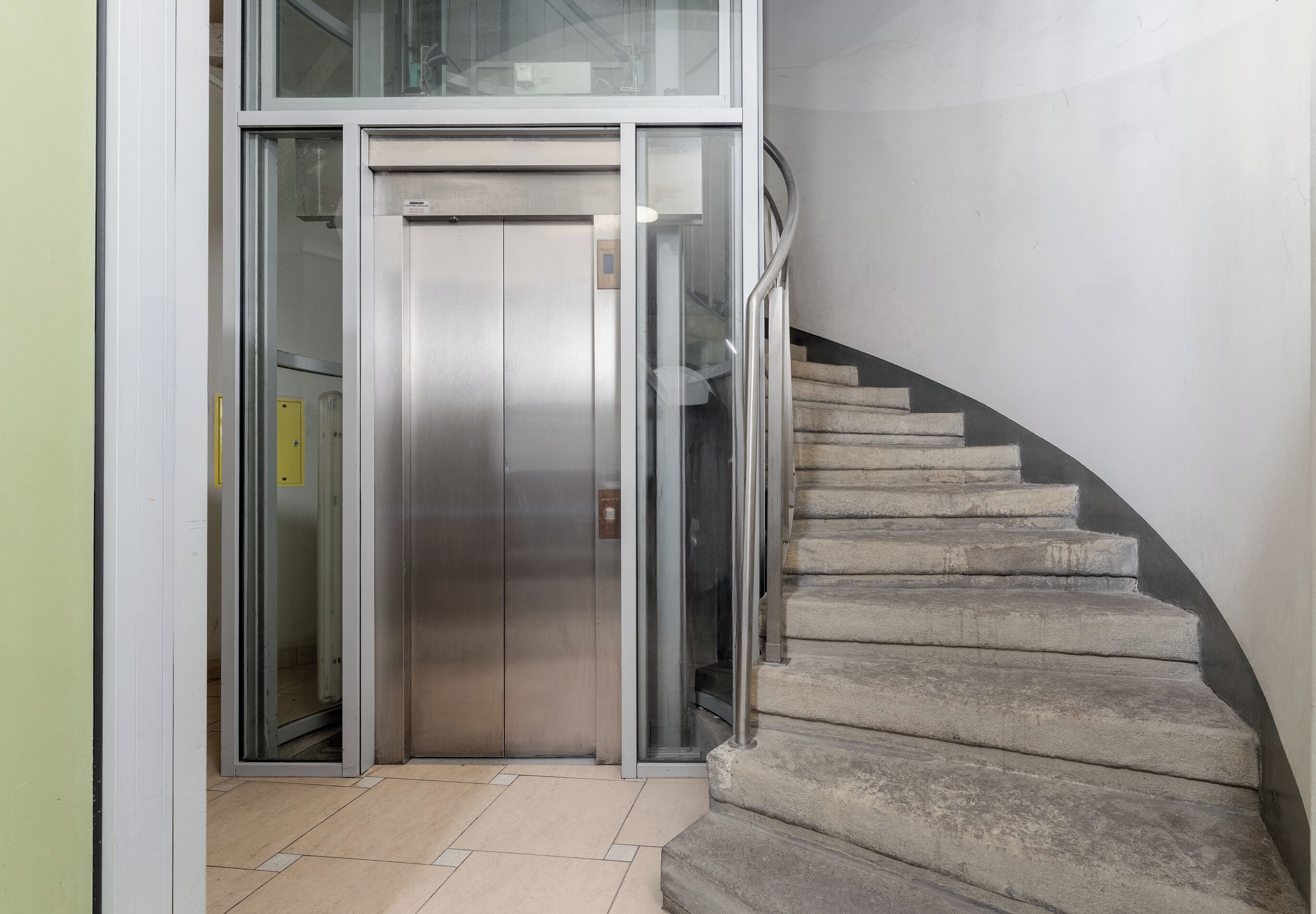 A modern elevator and a curved staircase in a building.