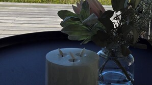 Een kaars op een tafel met uitzicht op een meer en een houten terras.