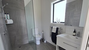 Een moderne badkamer met douche, toilet en wastafel.