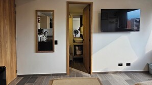 Moderni olohuone, jossa on suuri peili, seinälle asennettu taulutelevisio ja ikkunasta avautuva näkymä ulos.