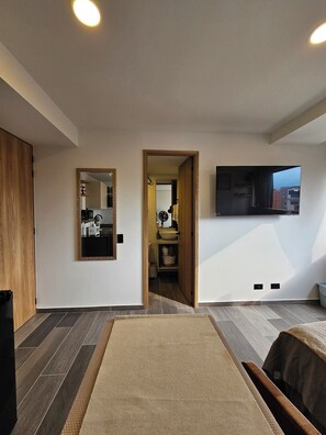 A modern living room with a large mirror, a flat-screen TV mounted on the wall, and a view of the outside through a window. - InnerBloom Your loft in the best neighborhood in Medellín, just 5 minutes from the stadium. (Medellín)