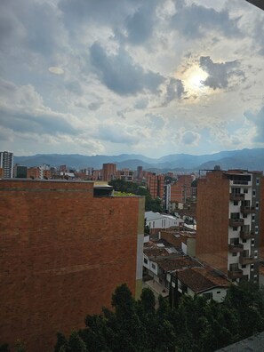 A cityscape with multiple buildings, including a prominent red brick building in the foreground and a white building with balconies in the background. - InnerBloom Your loft in the best neighborhood in Medellín, just 5 minutes from the stadium. (Medellín)