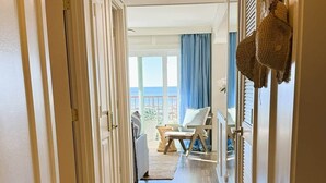A hallway leading to a balcony with a view, a wicker chair, and a small table. - Oceanfront Sanctuary in Hilton Head Island (Hilton Head Island)